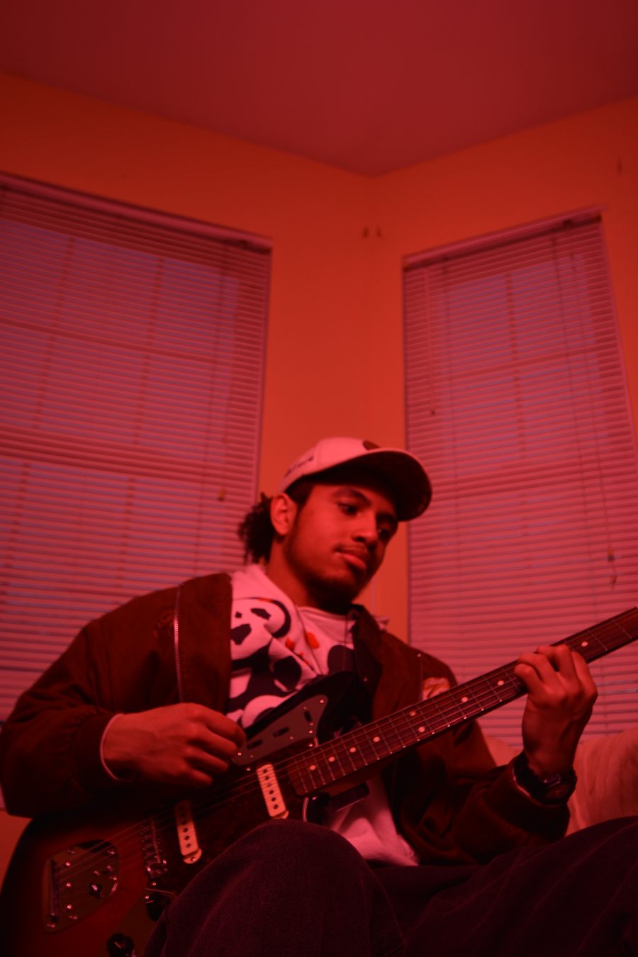 Billere looking down at his guitar neck, lit in red