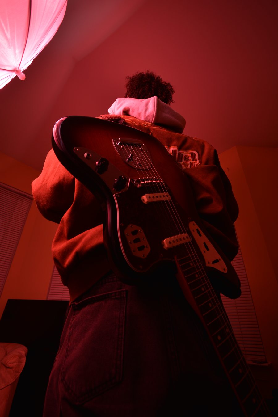 Billere with his back turned, the body of a Jaguar guitar across it