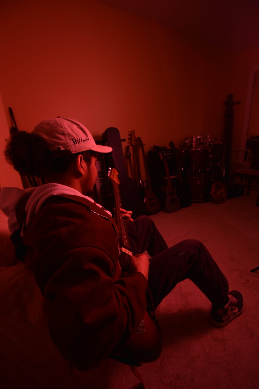 Billere playing guitar with his instruments and drums lined up behind him