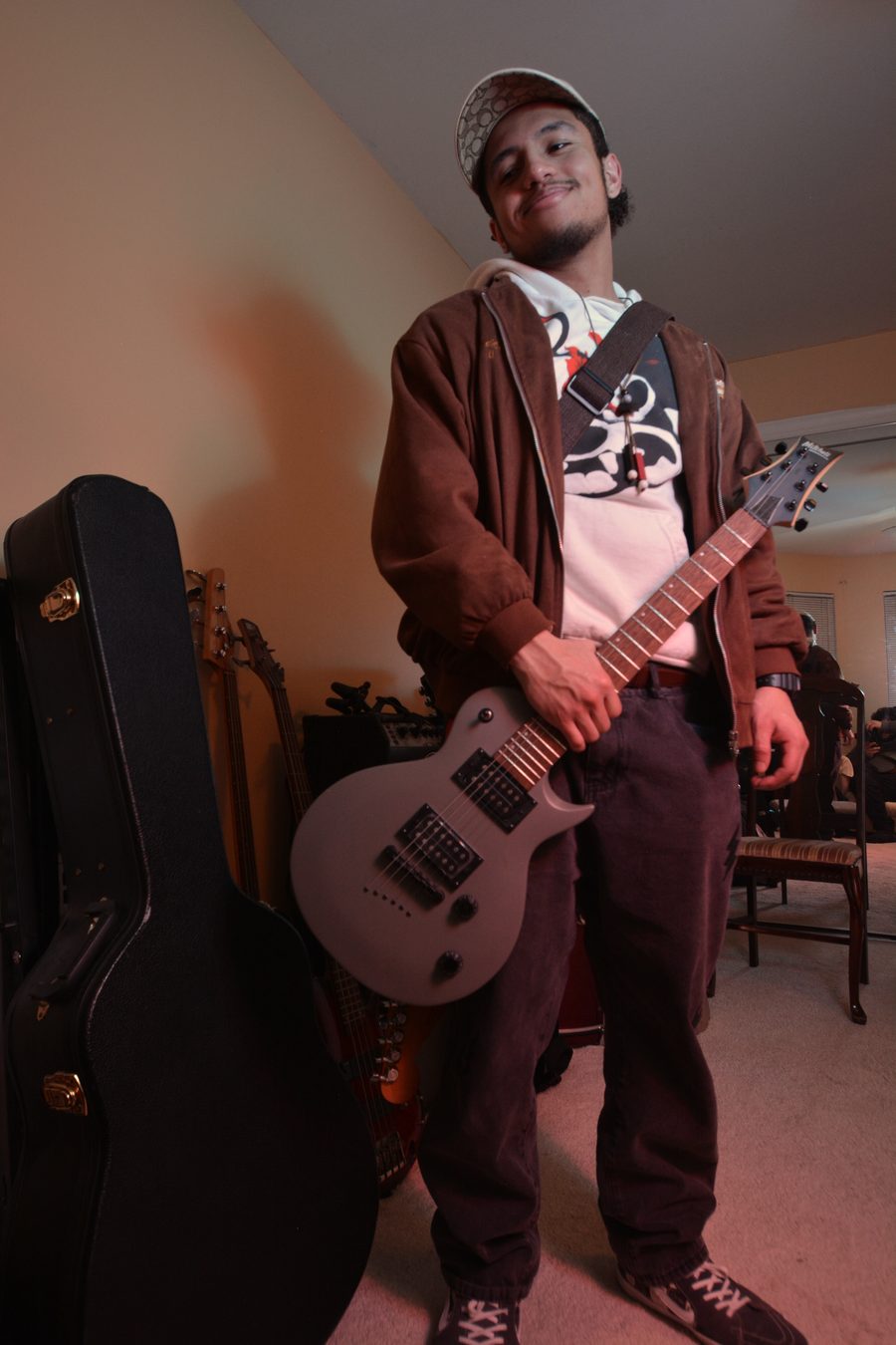 Billere smiling in his studio, holding a grey electric guitar